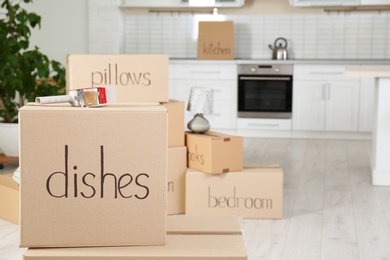 Photo of Moving boxes and adhesive tape dispenser in kitchen. Space for text