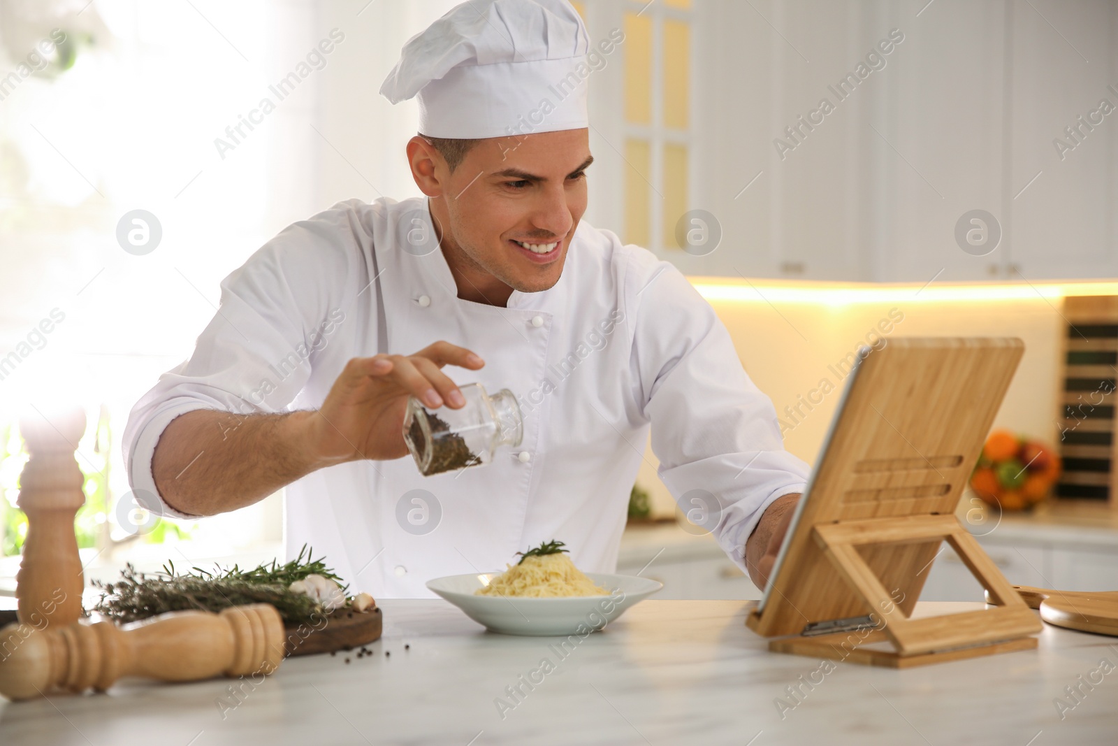 Photo of Chef with tablet cooking at table in kitchen