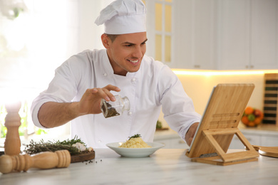 Chef with tablet cooking at table in kitchen