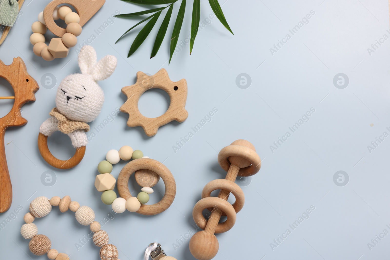 Photo of Different baby accessories and palm leaf on light blue background, flat lay. Space for text