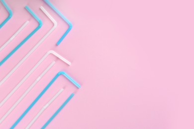 Colorful plastic drinking straws on pink background, flat lay. Space for text