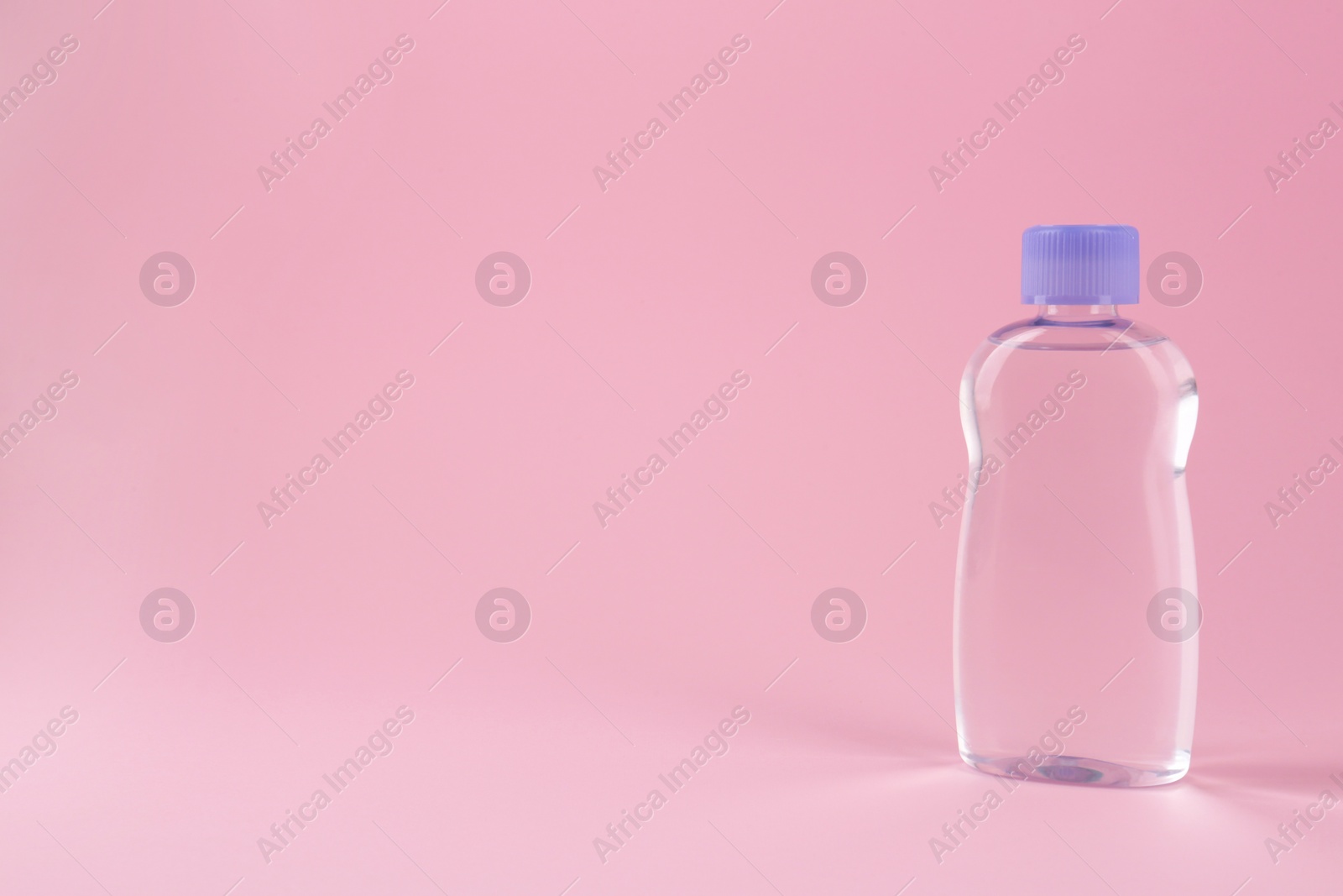 Photo of Bottle with baby oil on pink background, space for text