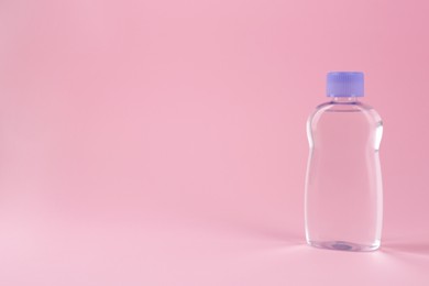 Photo of Bottle with baby oil on pink background, space for text