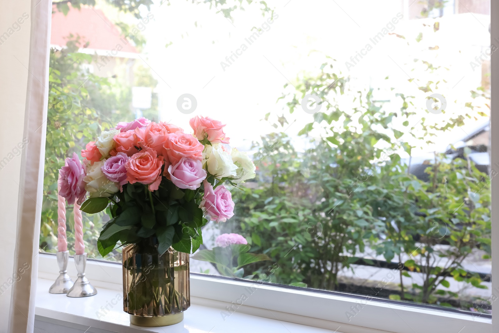 Photo of Vase with beautiful bouquet of roses and candles on windowsill indoors. Space for text