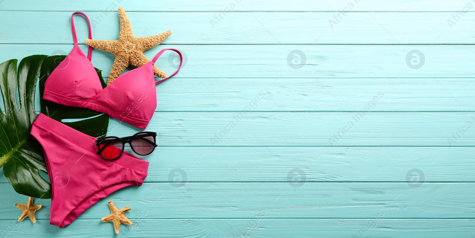 Photo of Beautiful pink bikini and beach accessories on light blue wooden background, flat lay. Space for text