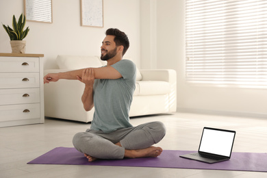 Man practicing yoga while watching online class at home during coronavirus pandemic. Social distancing