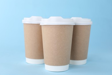 Photo of Paper cups with white lids on light blue background. Coffee to go