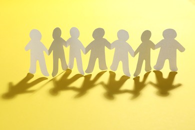 Photo of Paper people chain on yellow background. Unity concept
