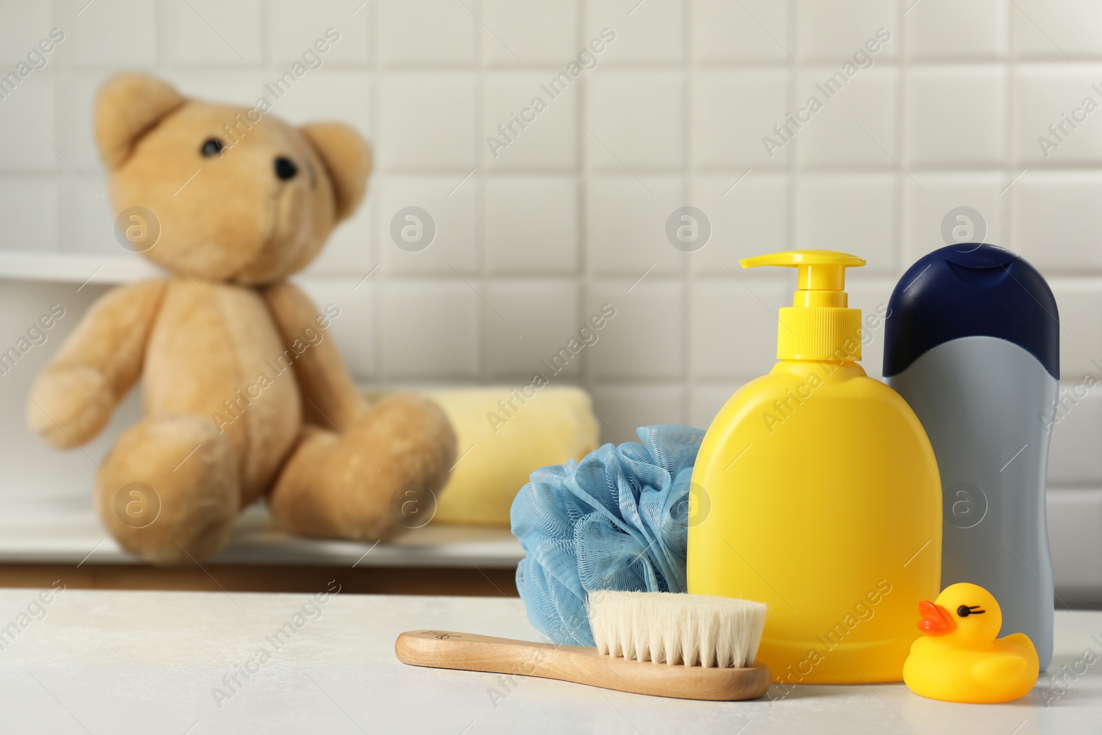 Photo of Baby cosmetic products, bath duck, brush and cotton swabs on white table. Space for text