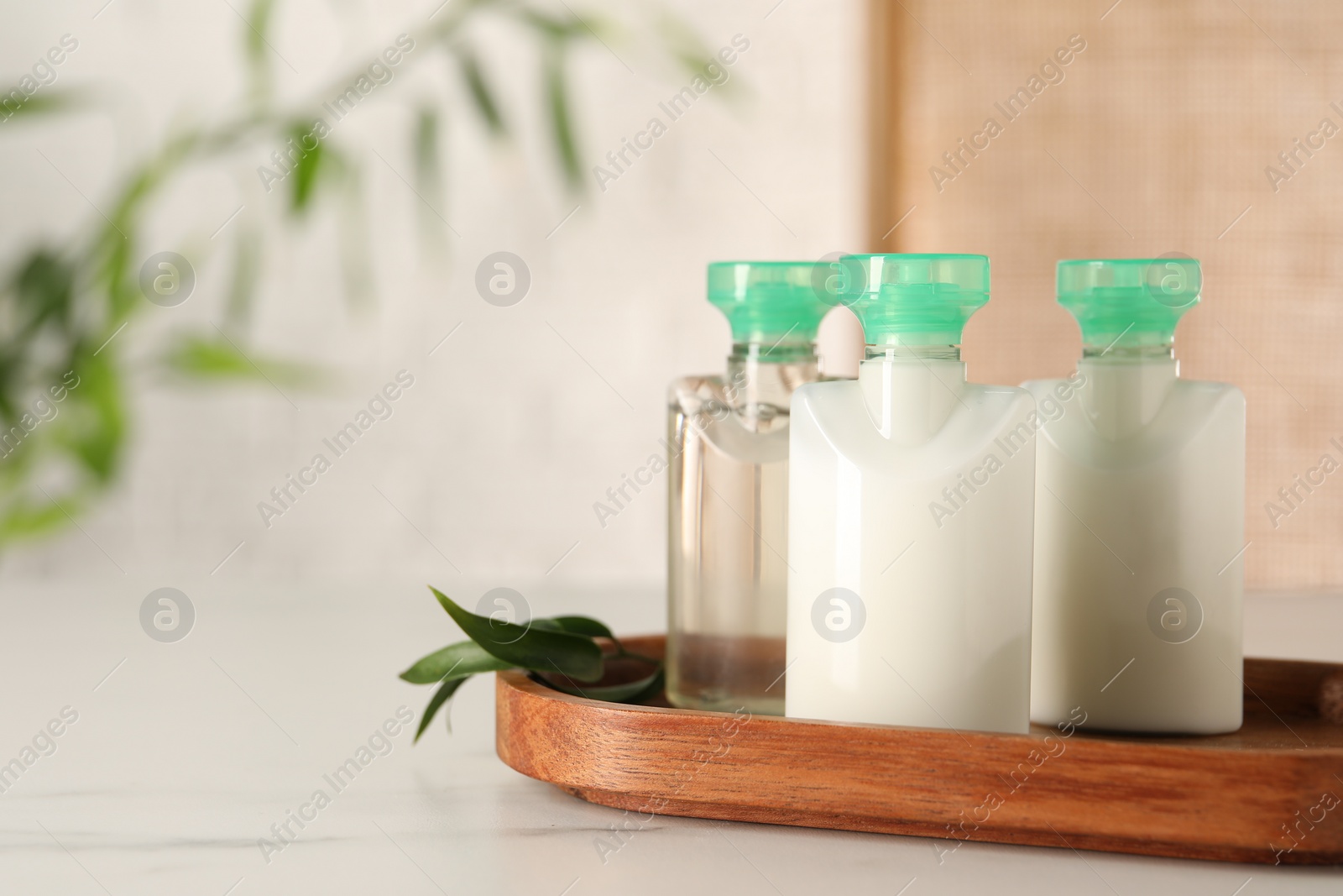 Photo of Mini bottles of cosmetic products on white table against blurred background. Space for text