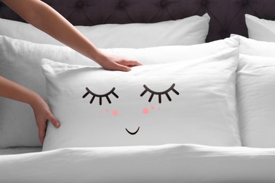 Image of Woman plumping pillow with cute face in bedroom, closeup
