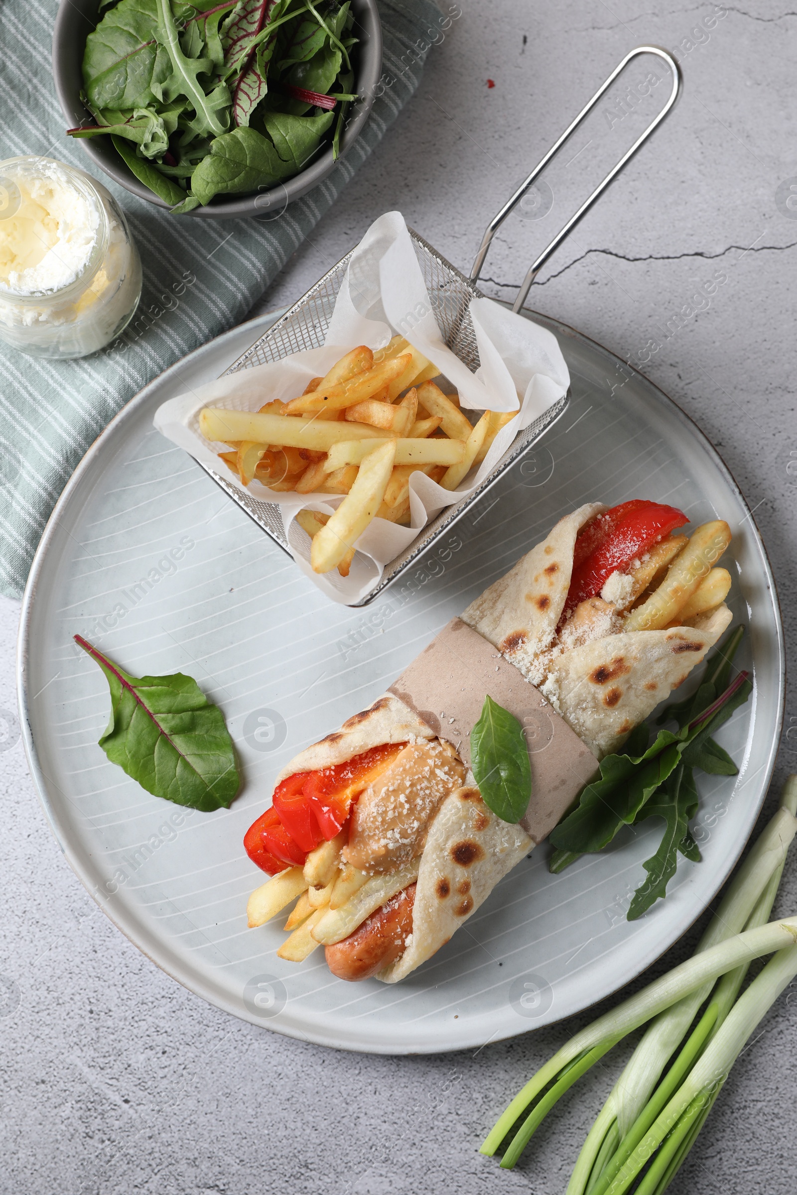 Photo of Delicious pita wrap with sausage, french fries and pepper on light gray table, flat lay