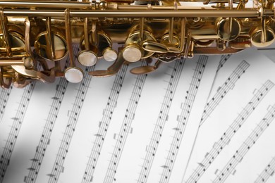 Photo of Beautiful saxophone on note sheets, closeup view