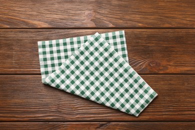 Photo of Green checkered tablecloth on wooden table, top view