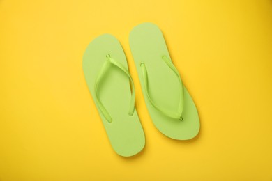 Photo of Stylish light green flip flops on yellow background, top view