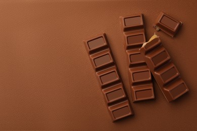 Delicious chocolate bars on brown background, flat lay. Space for text