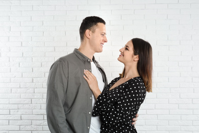 Photo of Happy young couple near white brick wall