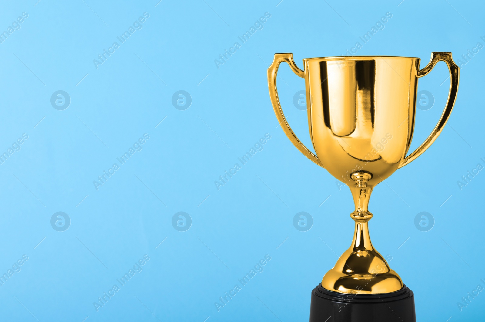 Photo of Golden trophy cup on blue background. Space for text