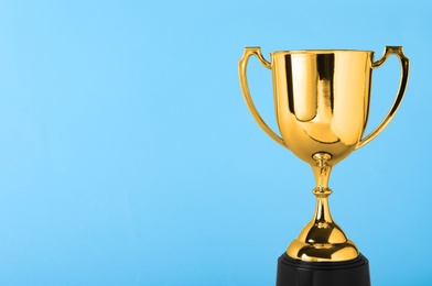 Golden trophy cup on blue background. Space for text