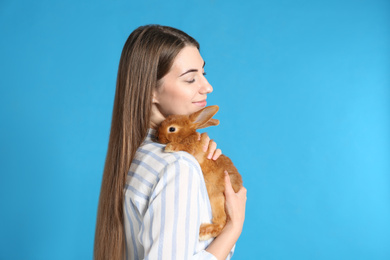 Photo of Young woman with adorable rabbit on blue background. Lovely pet