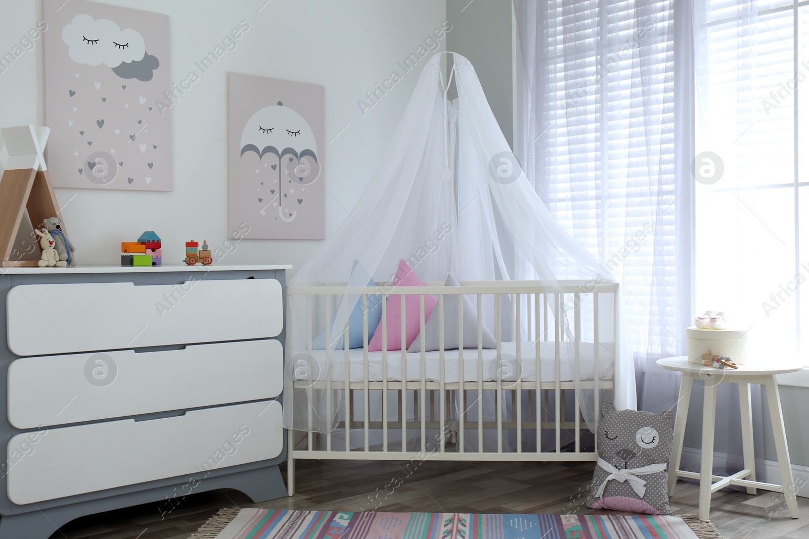 Photo of Baby room interior with cute posters, chest of drawers and comfortable crib