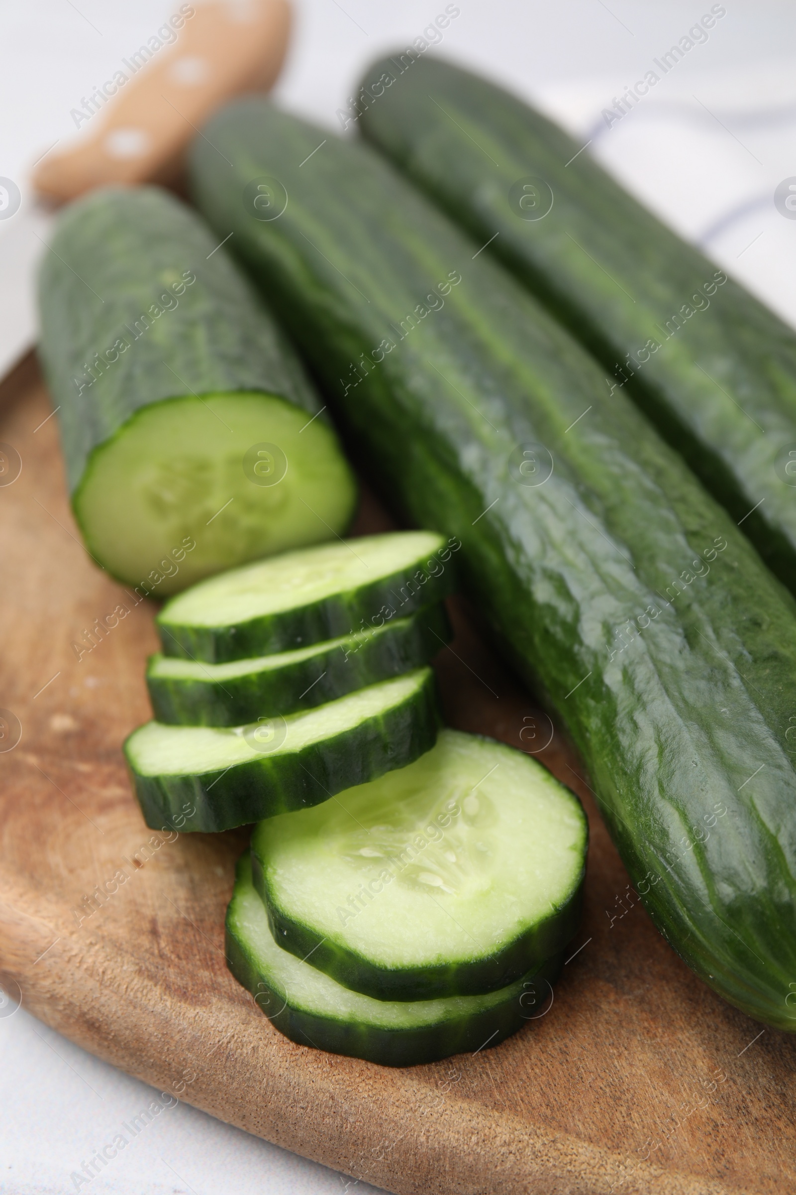 Photo of Fresh whole and cut cucumbers on table, closeup