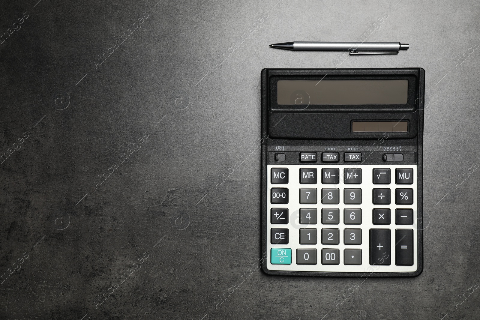 Photo of Calculator and pen on dark gray table, flat lay with space for text