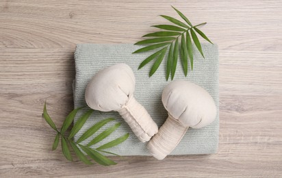 Photo of Beautiful spa composition with herbal massage bags and green leaves on light wooden table, flat lay