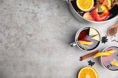 Photo of Tasty mulled wine with spices on grey table, flat lay. Space for text