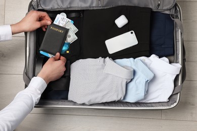 Man packing suitcase for business trip on wooden floor, top view