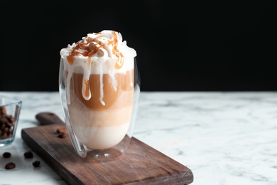 Photo of Glass with delicious caramel frappe on table