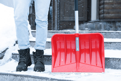Photo of Man with red snow shovel outdoors. Winter weather