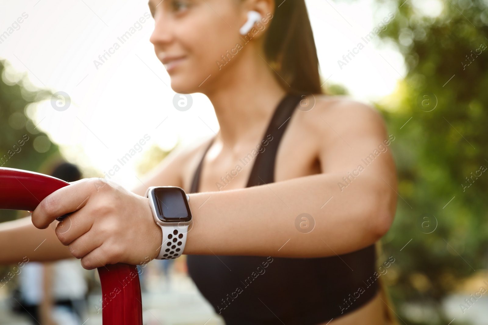 Photo of Woman wearing modern smart watch during training outdoors, closeup