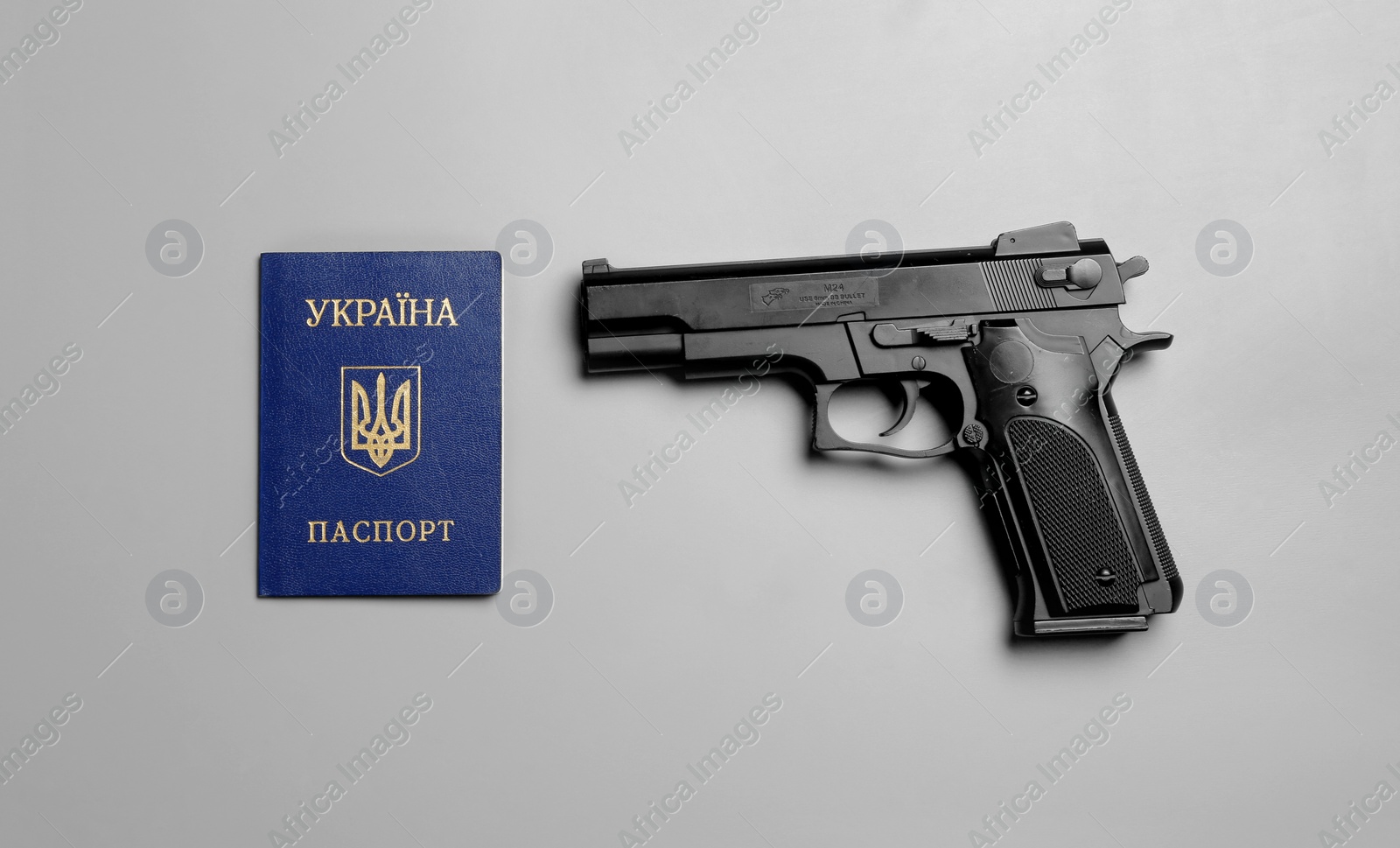 Photo of Gun with Ukrainian internal passport on grey background, flat lay