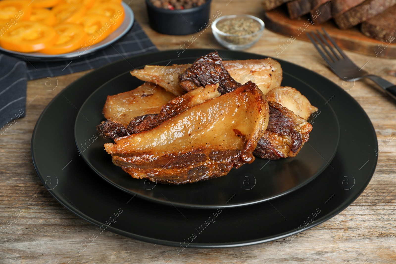 Photo of Tasty fried cracklings on wooden table, closeup. Cooked pork lard