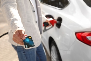 Man fills the car and giving credit card at gas station, closeup