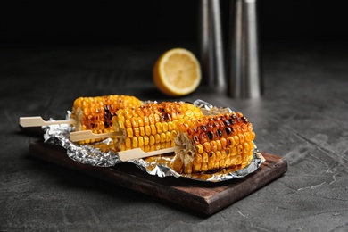 Photo of Delicious grilled corn cobs on gray table