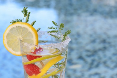 Photo of Delicious refreshing lemonade with raspberries near pool, closeup. Space for text