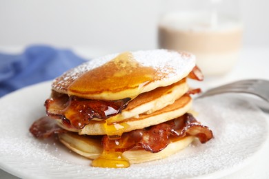 Photo of Delicious pancakes with maple syrup, sugar powder and fried bacon on plate, closeup