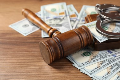 Judge's gavel and money on wooden table, closeup