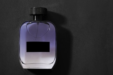 Photo of Luxury men`s perfume in bottle on black background, top view. Space for text