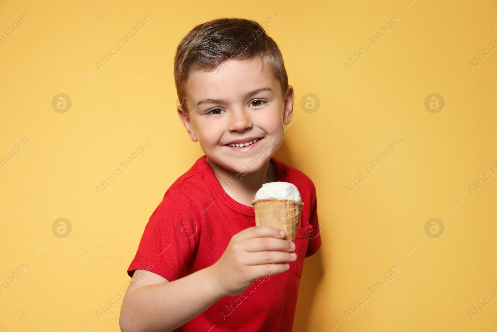 Photo of Adorable little boy with delicious ice cream against color background