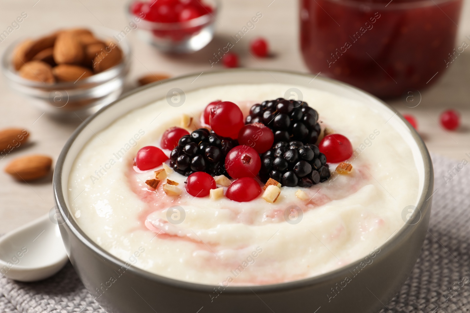 Photo of Delicious semolina pudding with berries in bowl on table, closeup