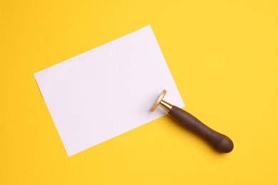 Photo of One stamp tool and sheet of paper on yellow background, top view. Space for text