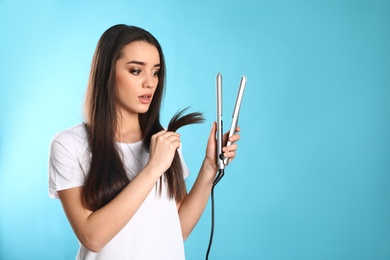 Photo of Emotional woman with hair iron on color background. Space for text