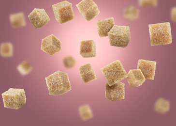 Image of Brown cane sugar cubes falling on dark pink gradient background