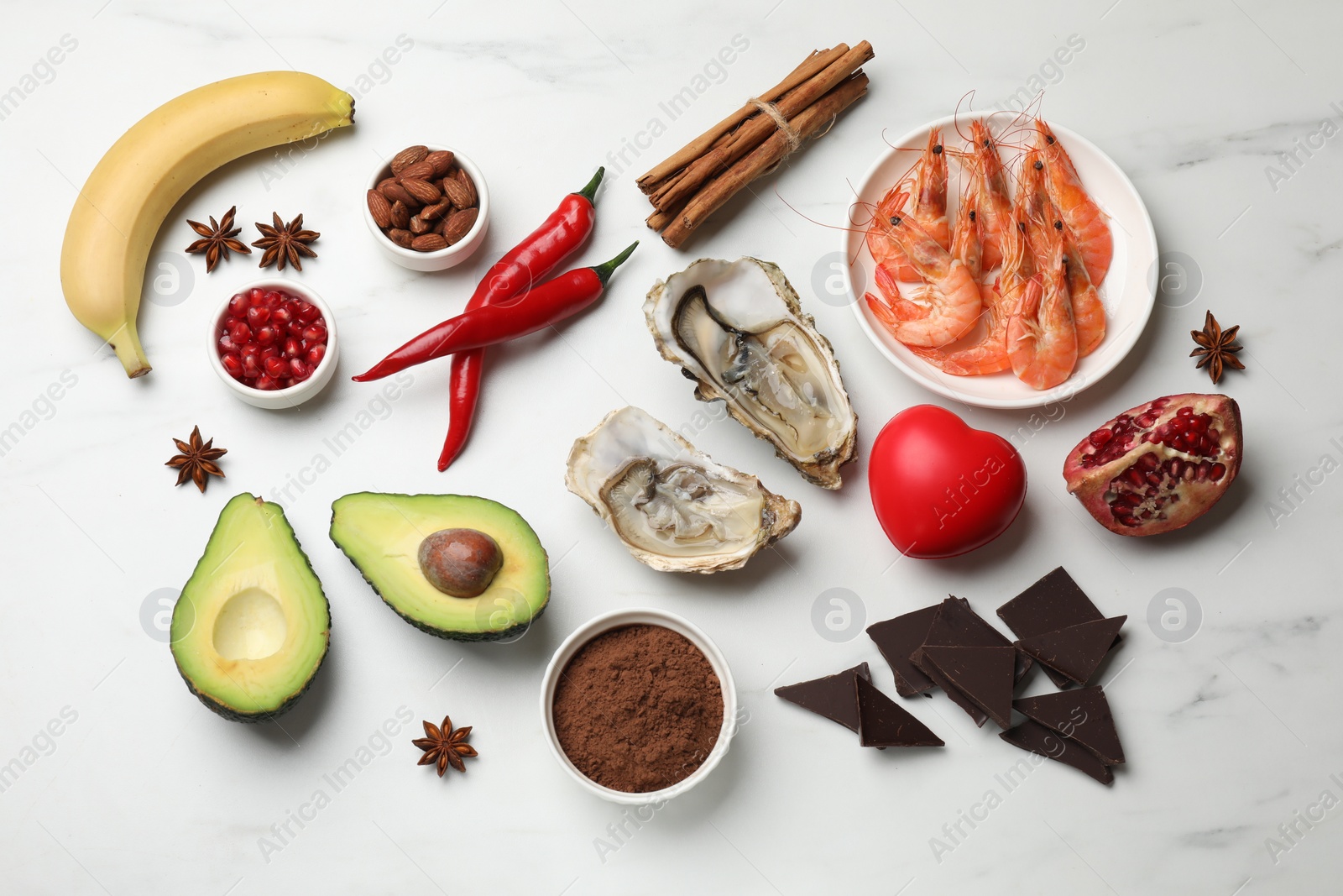 Photo of Natural aphrodisiac. Different food products and red decorative heart on white marble table, flat lay