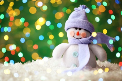 Image of Cute snowman on snow against green background, bokeh effect. Space for text