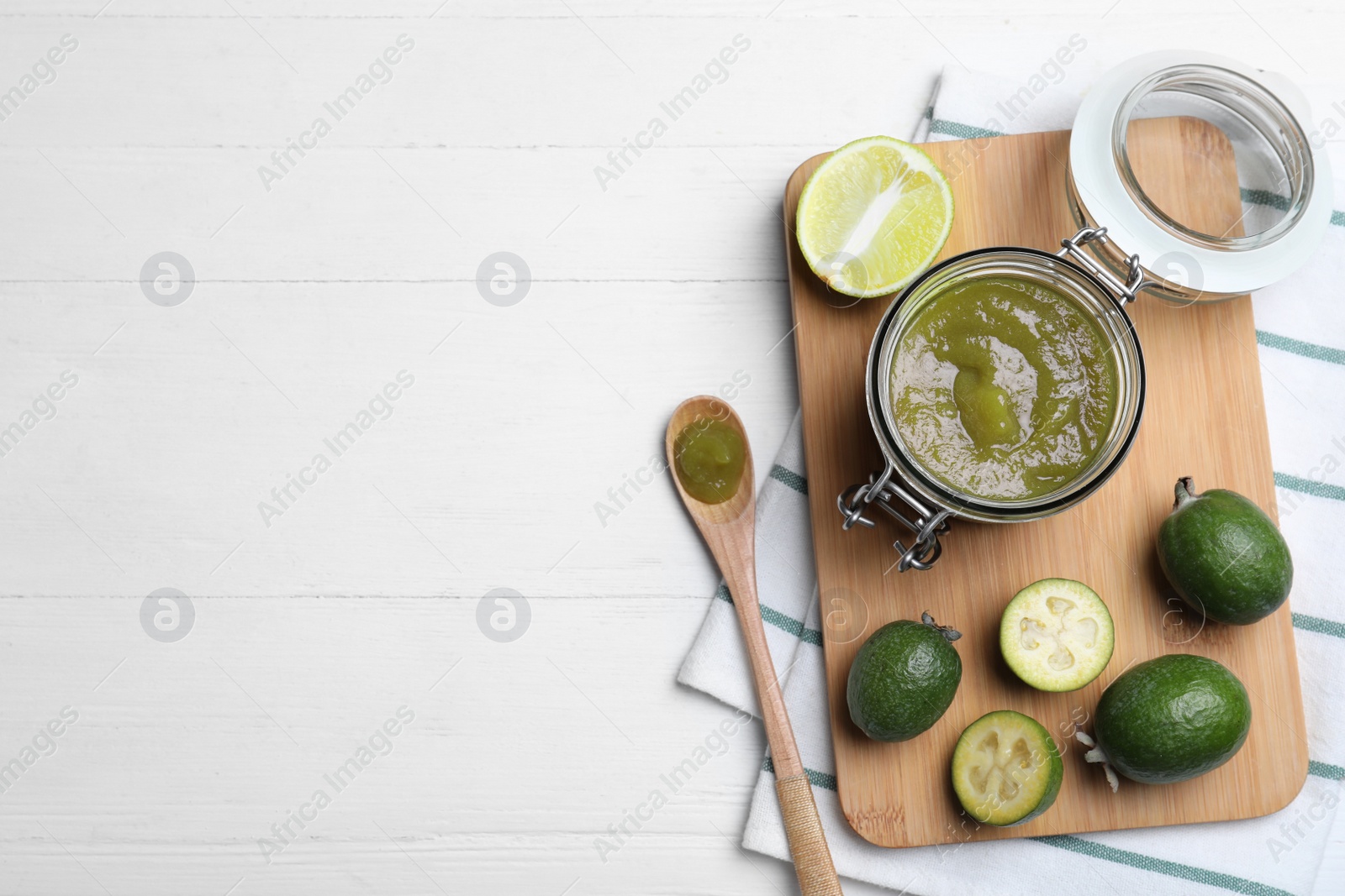 Photo of Feijoa jam and fresh fruits on white wooden table, flat lay. Space for text