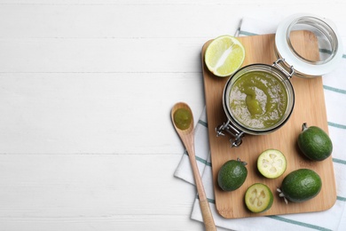 Feijoa jam and fresh fruits on white wooden table, flat lay. Space for text